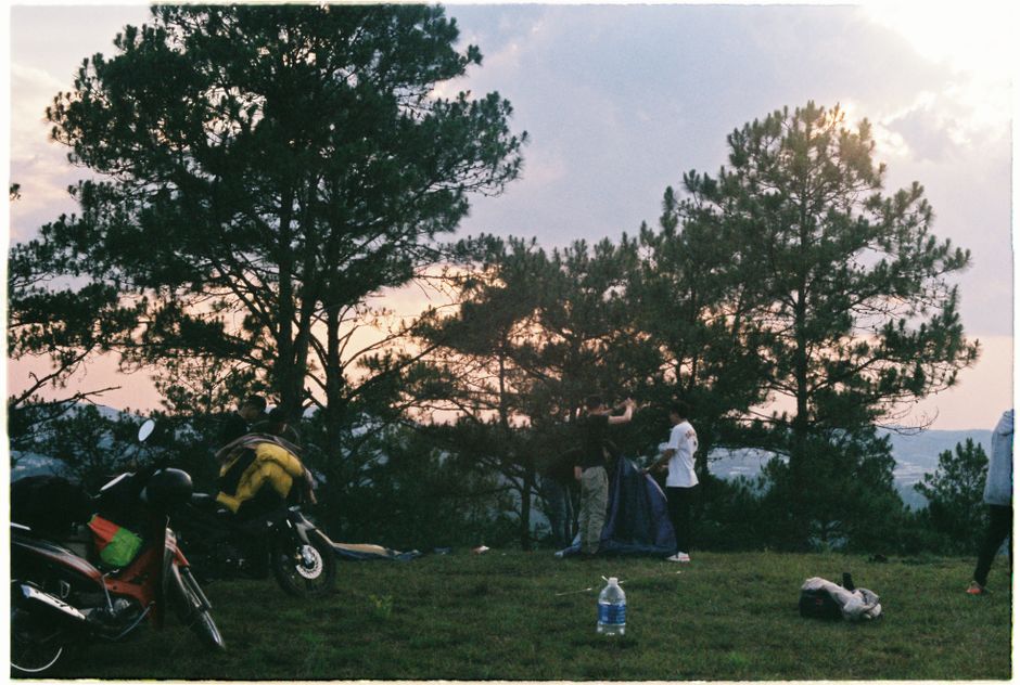 Group setting up camp with tents and motorbikes under evening sky